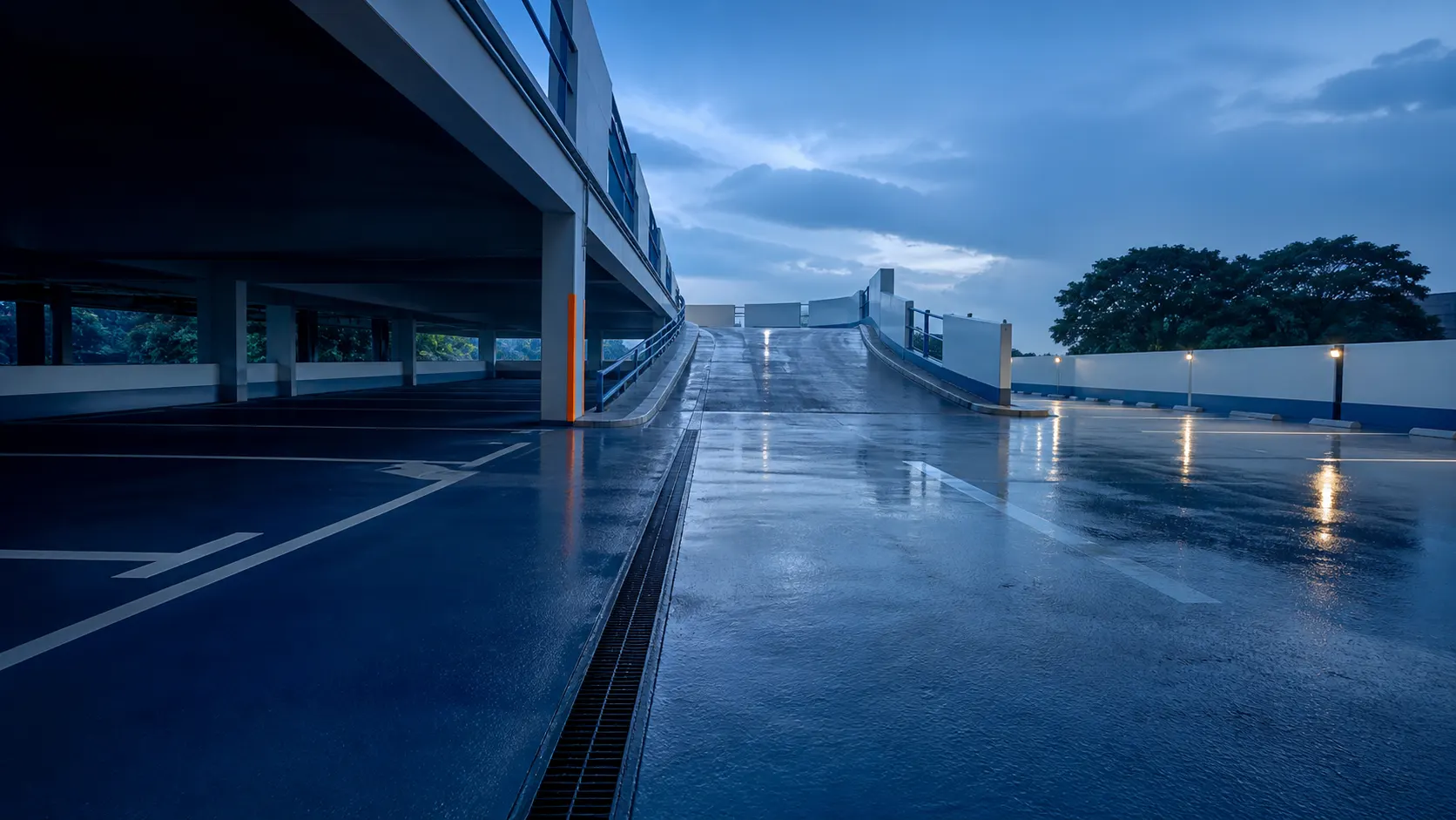 Car-park deck coating environment connecting sheltered bays, a wet ramp and an exposed upper deck