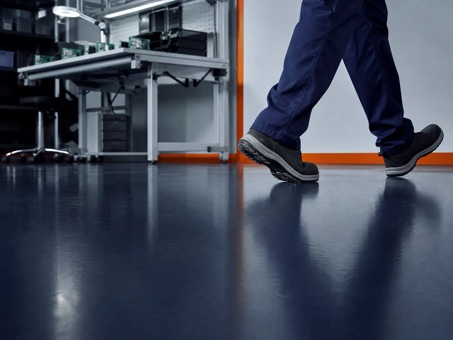 ESD-safe footwear moving across a seamless conductive floor in an electronics facility