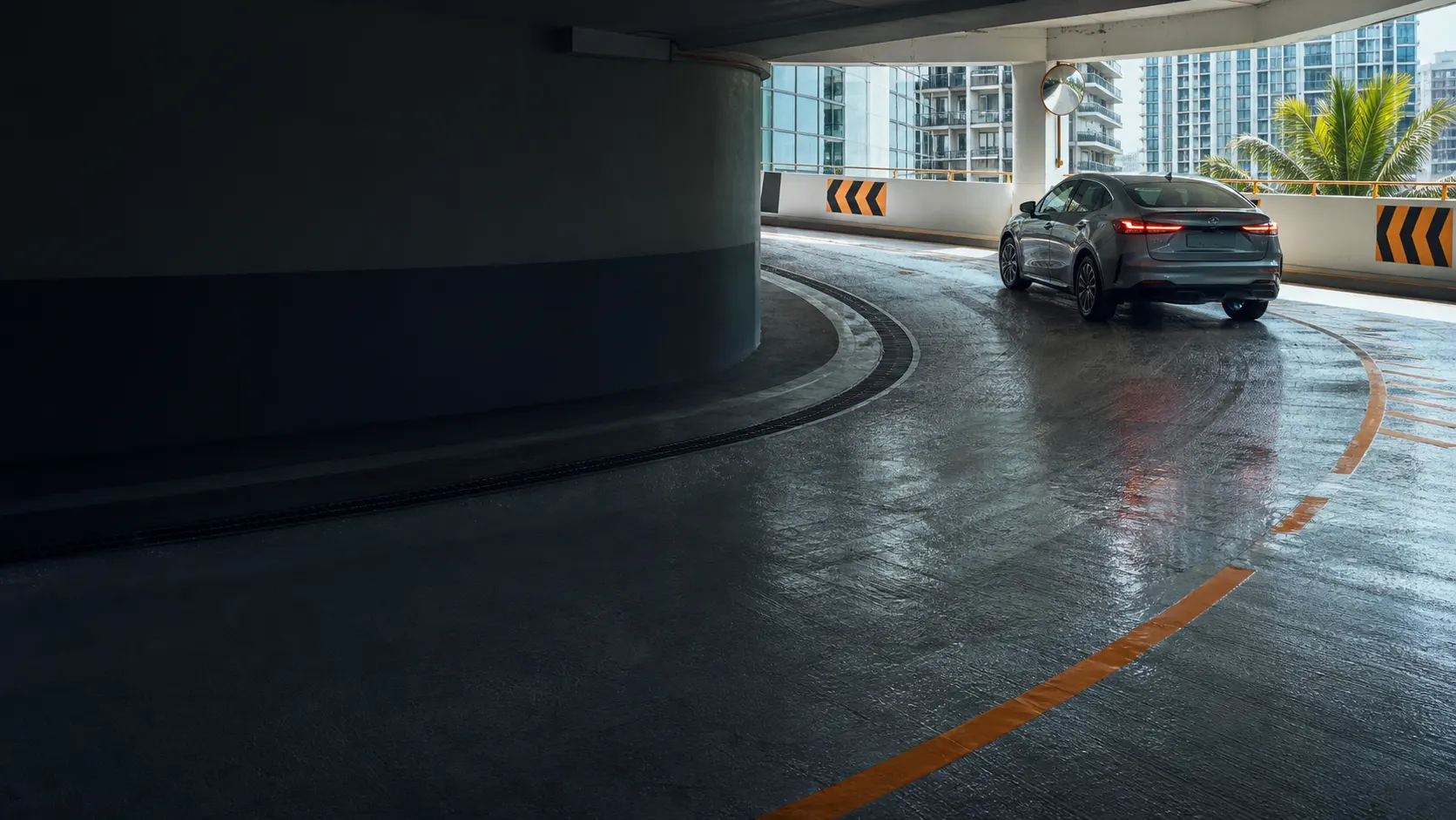 A wet multi-storey car-park ramp exposed to turning tyres, tracked rainwater and tropical sunlight